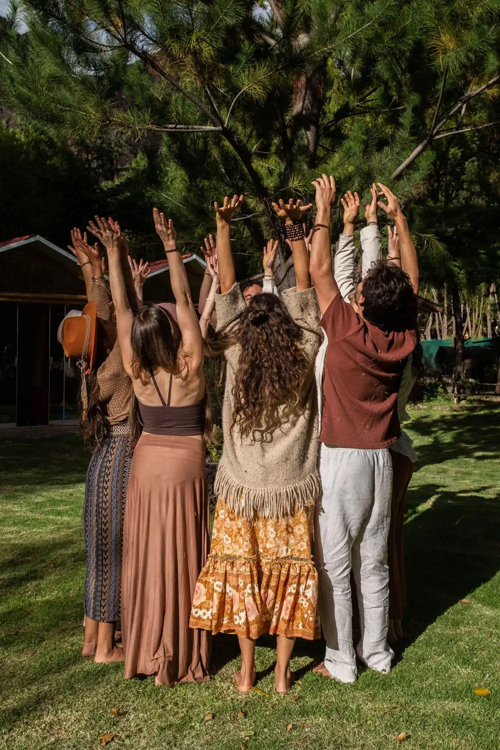 A sharing circle gathered on the grass with instruments and mountain views